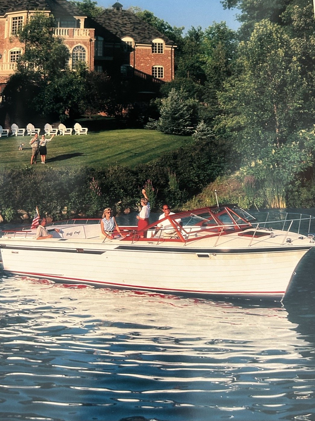 Skiff Craft runabout cruising past a lakeside home.