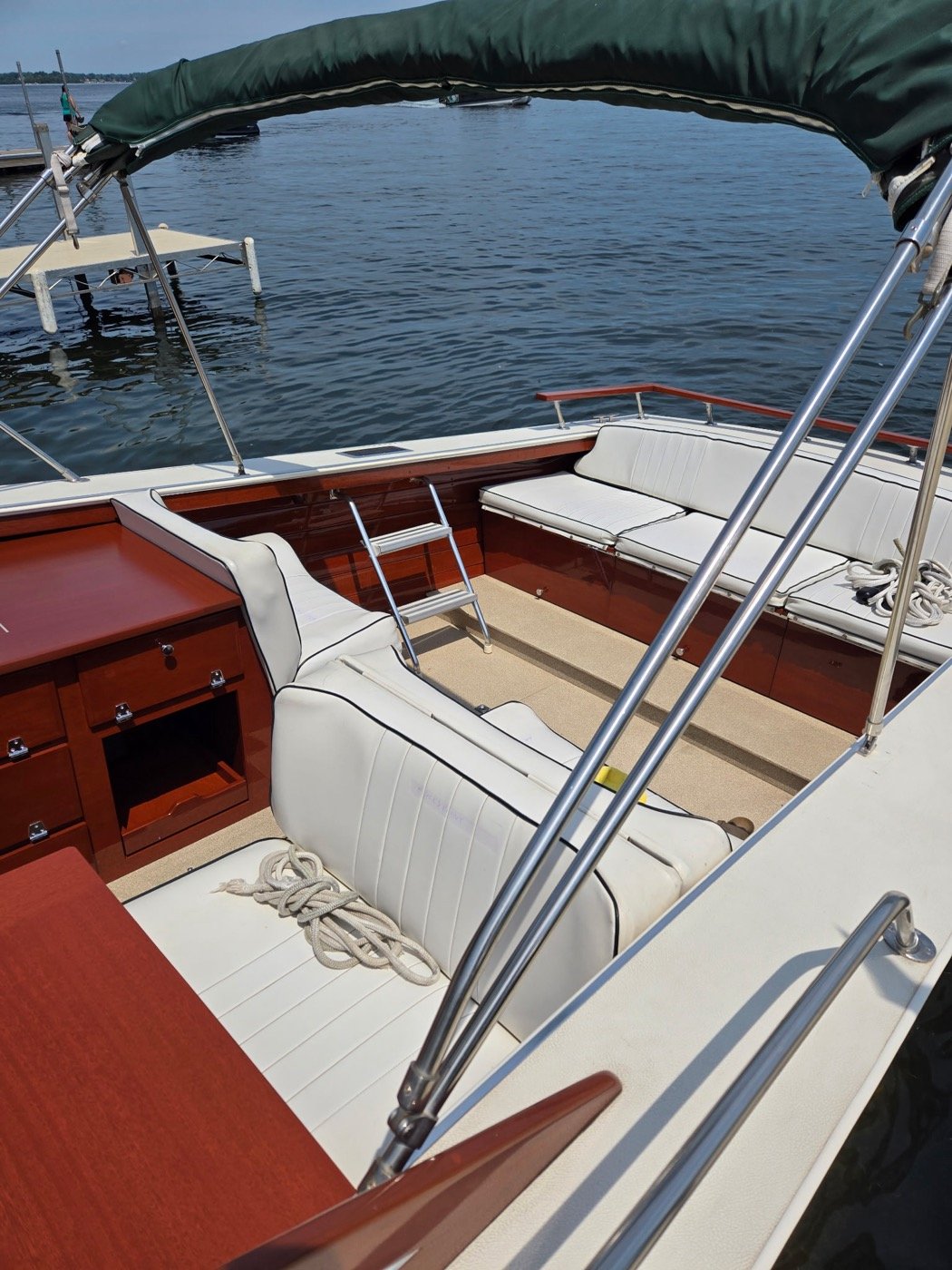 Skiff Craft cockpit with green bimini, ladder and white seating.